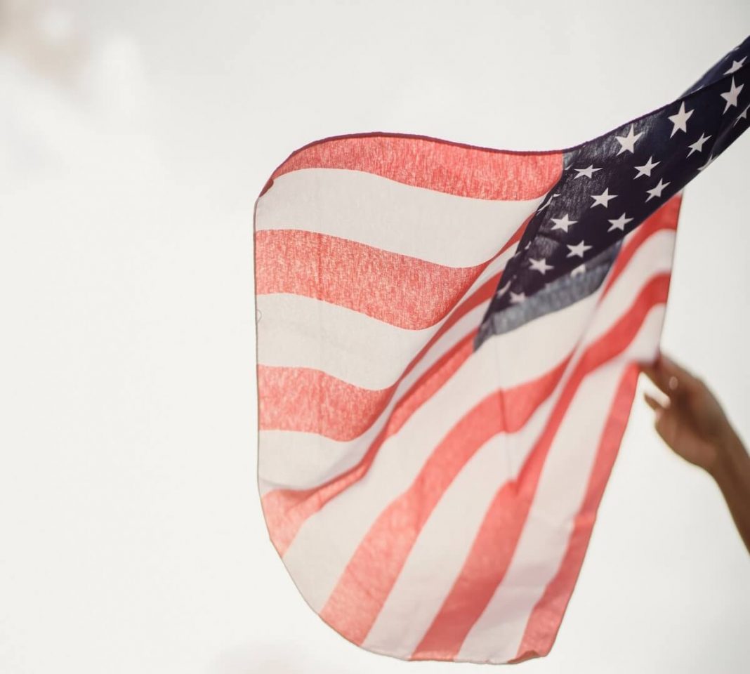 person holding us flag in front of sunlight