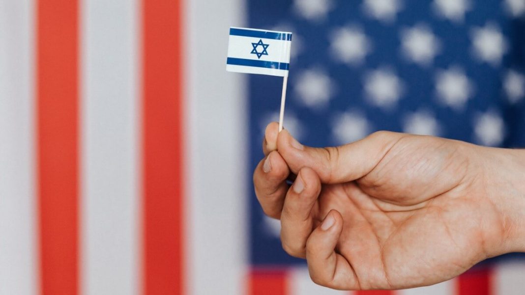 person holding israel flag us flag in the background