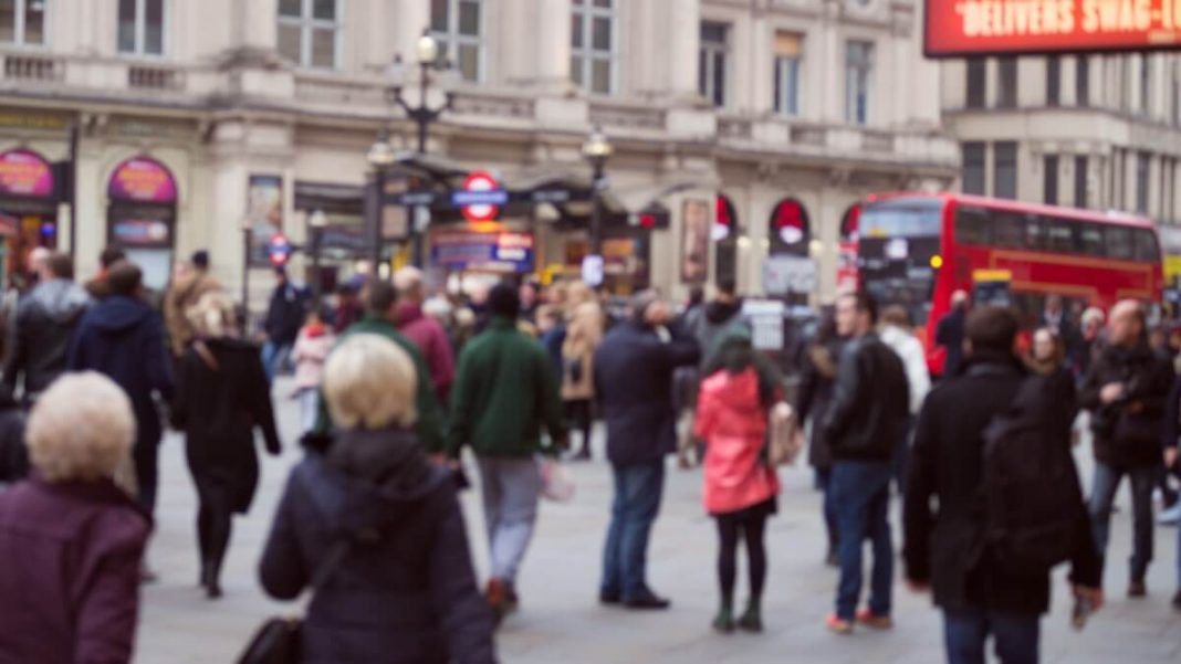 groups of people on london street near red bus and beige building