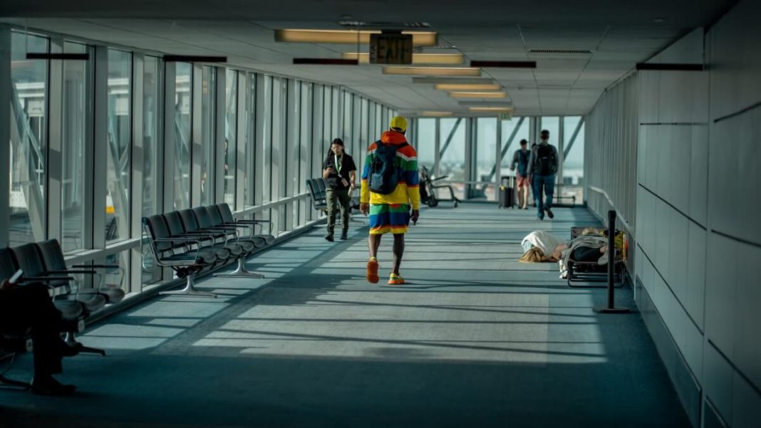 man with colorful clothing walking on airport hallway