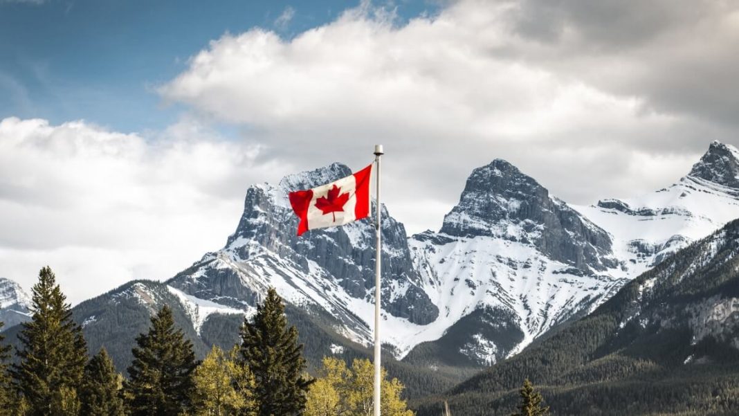 canada flag waving on flagpole mountain view