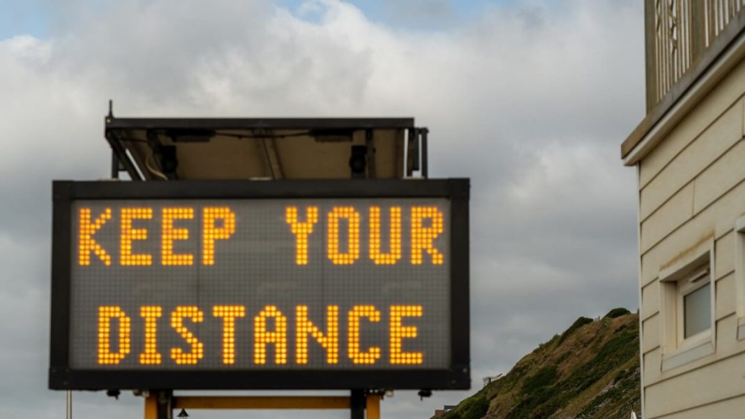 keep your distance yellow text sign