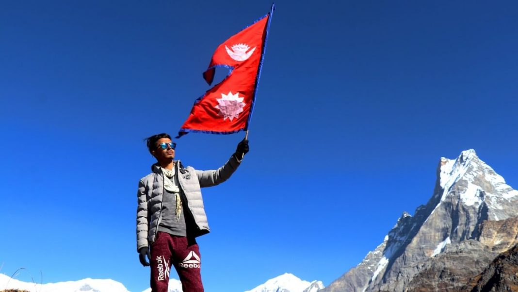 man holding nepal flag with mountain in the background