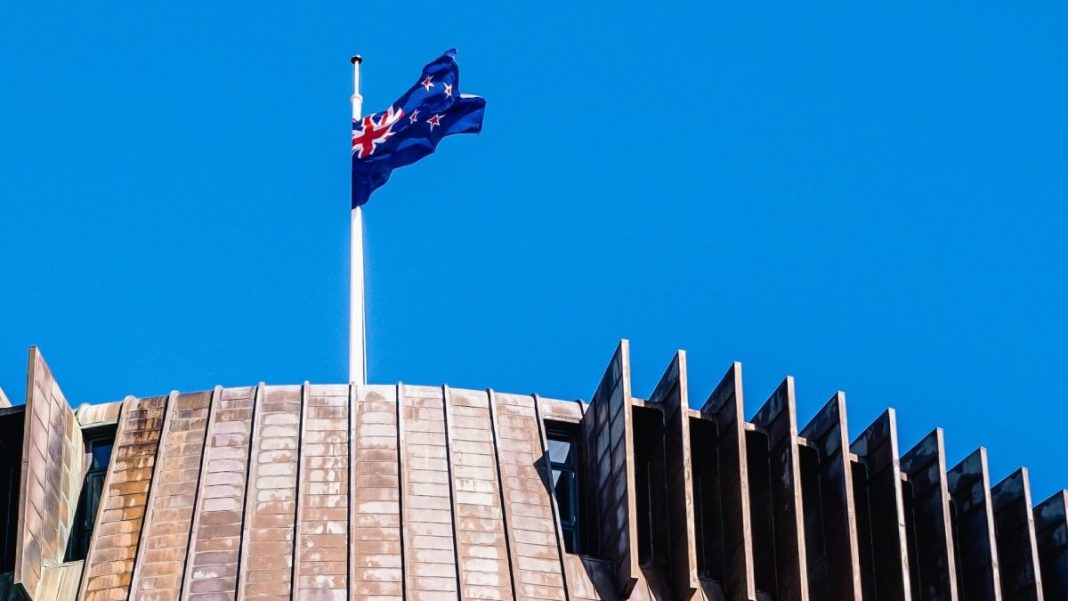 new zealand flag waving sky building background