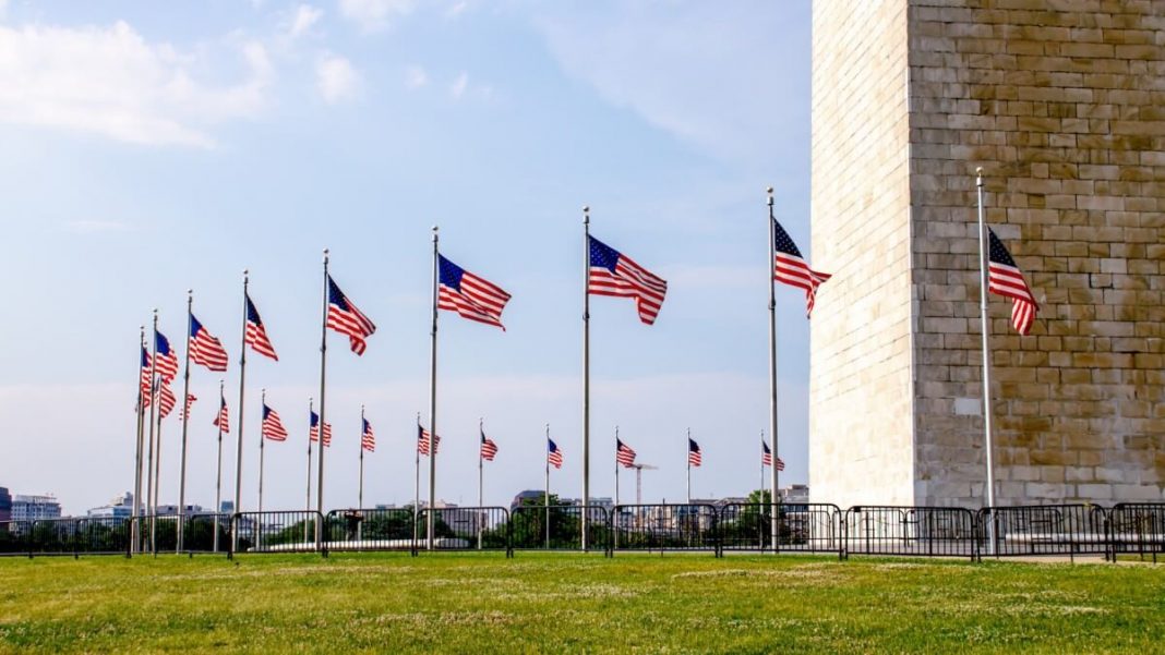 several us flags surrounding white building
