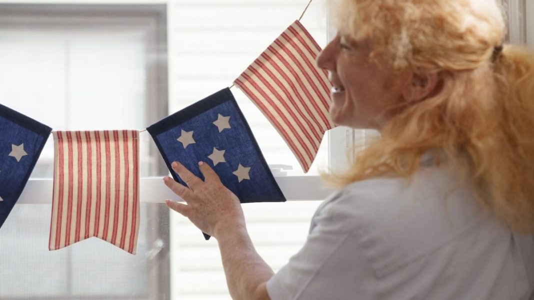 woman with white shirt hanging us flag buntings