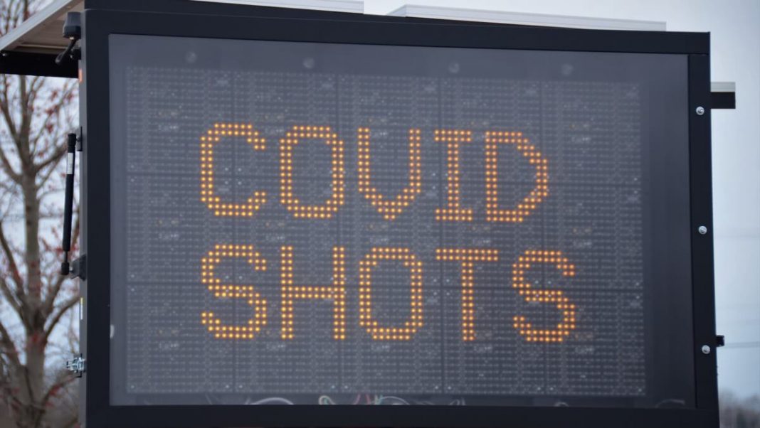 covid shots black and yellow traffic sign