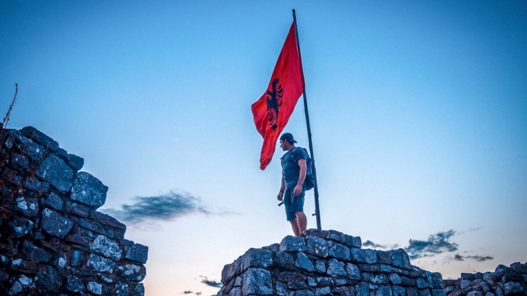 backpacker near albanian flag hanging on castle