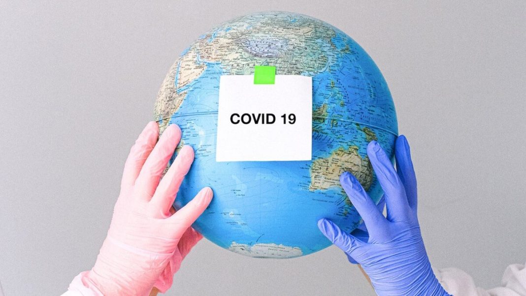 people with gloves holding globe with covid-19- note