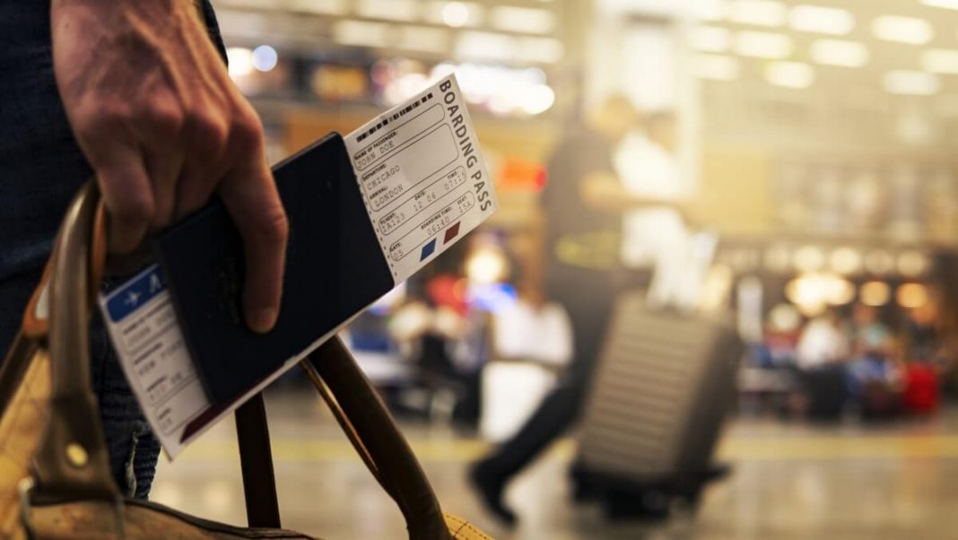 person holding passport with plane ticket