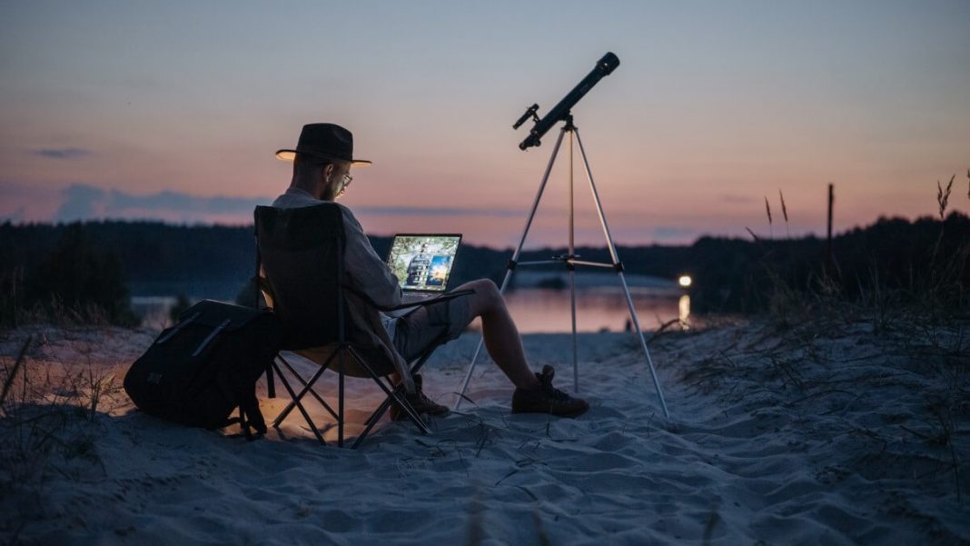 person working in laptop at the beach near telescope