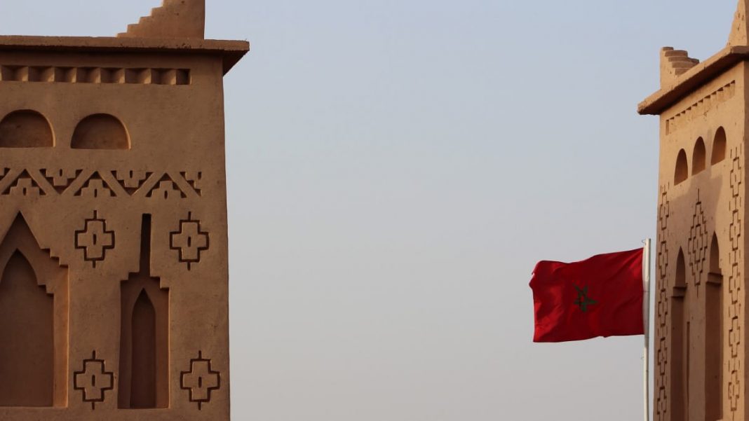 morocco flag waving next to beige concrete building