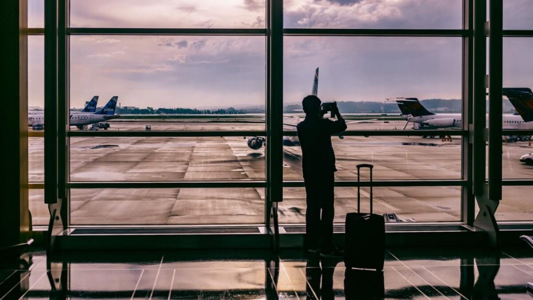 silhouette of man traveler with luggage at airport taking photo