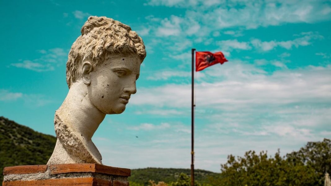 statue in butrint with albanian flag in the background