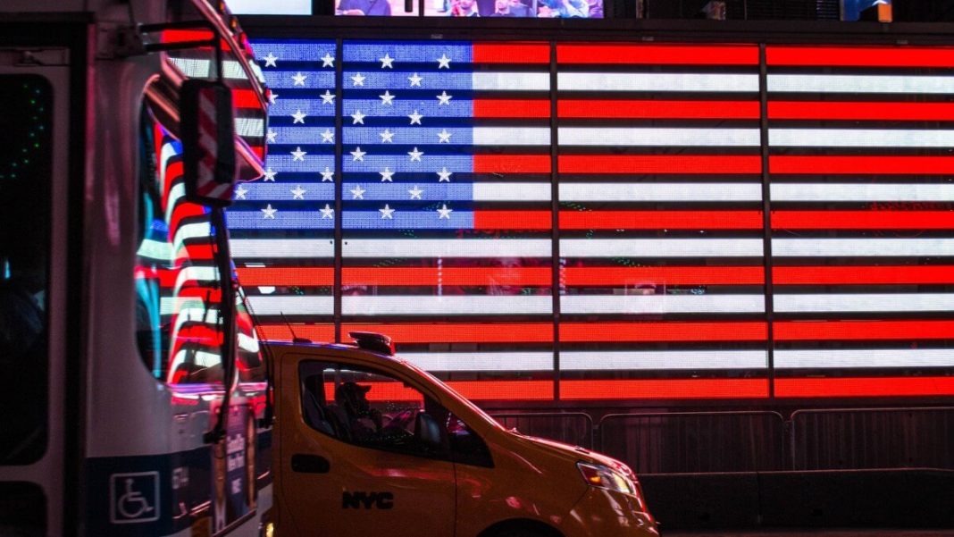 taxi and truck in front of us flag on big screen
