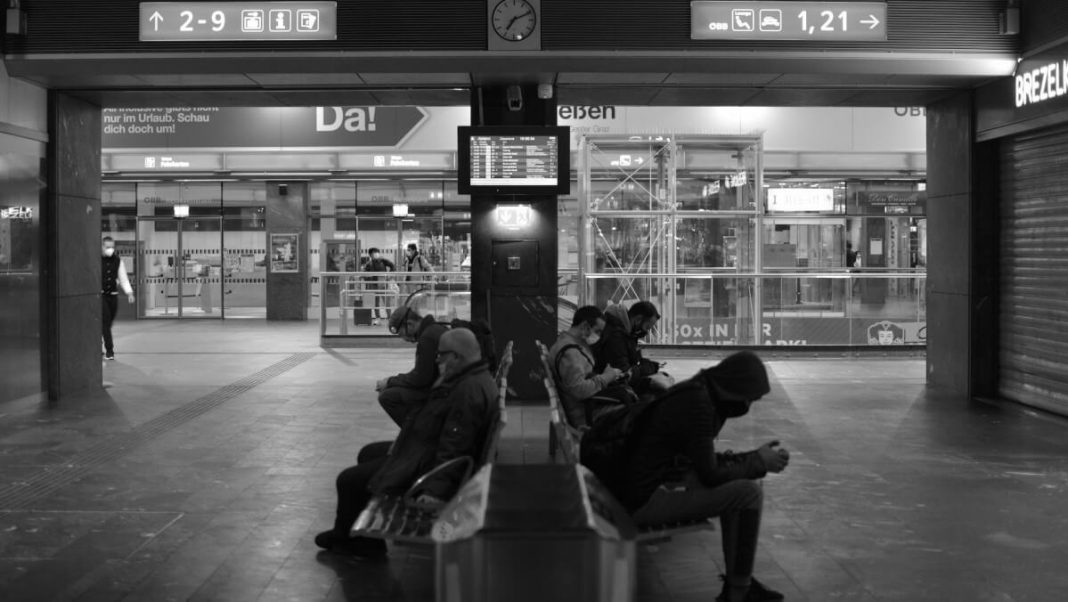 black and white picture travelers with masks sitting at airport hall