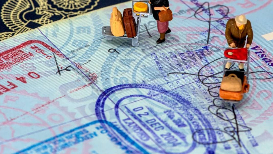 people figurines with luggages walking on visa stamped passport page