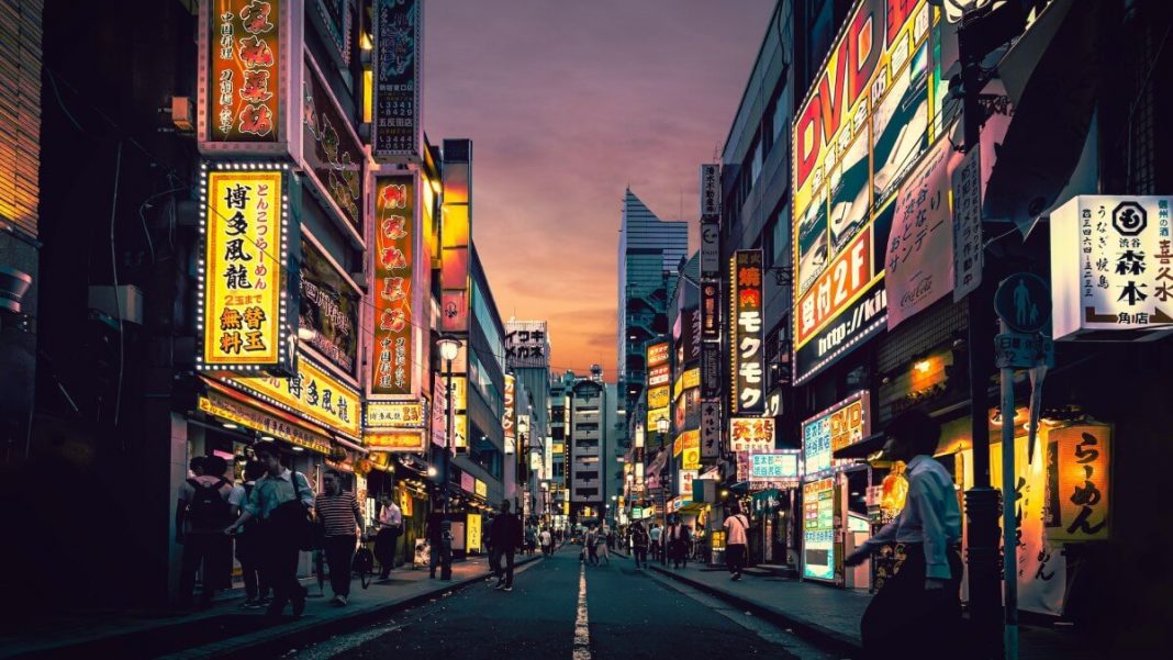 people walking next to japan tokyo buildings with neon signs