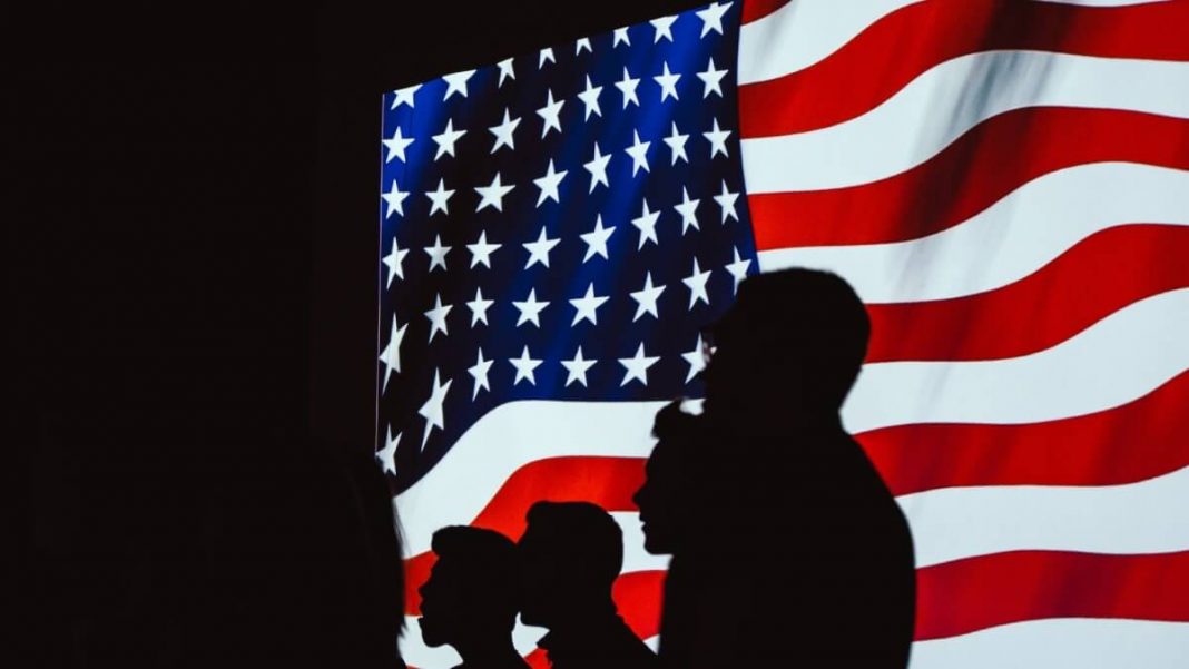 silhouettes of people in front of usa flag on screen