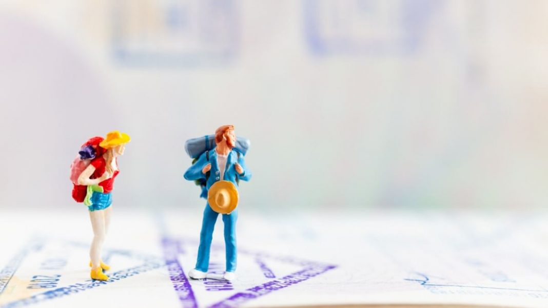 Miniature Travelers Walking on Passport